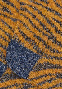 Strickstoff in lebendigen Orange- und Blautönen mit einem strukturierten Zickzackmuster. Weiche, flauschige Oberfläche mit einem kontrastierenden blauen Bereich.