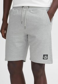 Shorts en mélange de coton gris avec une taille élastique, un cordon de serrage, des poches latérales et un patch logo noir à l'ourlet. Texture lisse.