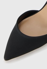 Mustat kärkitossut, jotka on valmistettu sileästä materiaalista, jossa on beige sisäpohja ja ohut, joustava pohja. Ei näkyviä metalliosia tai koristeita.