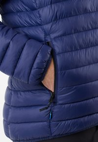 Marine blauwe pufferjack met een gequiltde textuur, zijritszak en elastische manchetten. Lichtgewicht materiaal geschikt voor koudere weersomstandigheden.