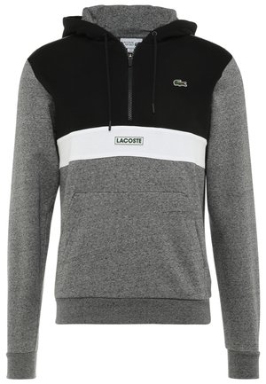 Grå og sort hættetrøje med hvid horisontal stribe, frontlomme, lynlåsåbning ved halsen og Lacoste-logo på brystet og striben.