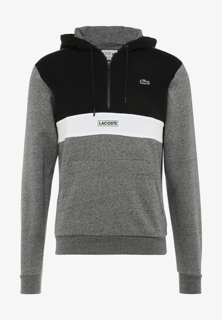 Sweat à capuche gris et noir avec une bande horizontale blanche, une poche avant, une fermeture éclair au niveau du col et le logo Lacoste sur la poitrine et la bande.