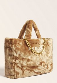 Torebka z sztucznego futra w jasnobrązowym kolorze, o pluszowej fakturze, z złotym łańcuszkiem i wytłoczonym logo z przodu.