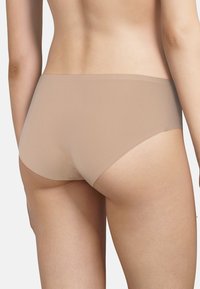 Beige naadloze ondergoed, gemaakt van een glad materiaal, met een volledige snit en minimale stitching voor comfort. Geen extra versieringen.
