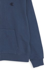Felpa con zip blu navy realizzata in misto cotone, dotata di tasca frontale, polsini e orlo a coste, con un logo ricamato discreto sul petto.