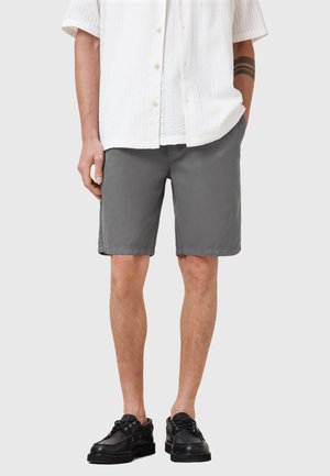 Grijze katoenen shorts met een rechte snit, zijzakken en een gladde textuur, gecombineerd met een wit overhemd met korte mouwen en zwarte schoenen.