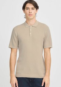 Beige színű, rövid ujjú polo-póló, texturált bordázott mintával, három gomb a gallérnál és szabott fazonnal. Sima kötött anyag.