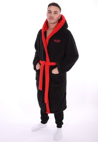 Zwarte fleec bathrobe met een rode capuchon en riem, voorzien van dubbele voorzakken en een geborduurde "Stranger Things" logo op de borst.