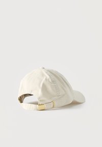 Καπέλο μπέιζμπολ από καραβόπανο χρώματος κρέμα με ρυθμιζόμενο λουράκι και μεταλλικό κούμπωμα σε λευκό φόντο.