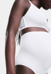 Witte zwangerschapsbh met kantdetails en witte hooggehal lente onderbroek. Gladde stof met een gefit en naadloos ontwerp. Strakke pasvorm rond de buik.