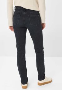 Jeans in denim scuro con una vestibilità slim, dotati di tasche posteriori e vita media. Accentuati da una leggera texture e cuciture minime.