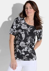 T-shirt noir à manches courtes avec des motifs floraux et paisley blancs, col rond et silhouette ajustée. Fabriqué en tissu doux et extensible.