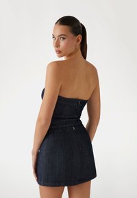 Donkerdenim strapless jurk met een aansluitende lijfje en een korte rok. Bevat een verborgen rits aan de achterkant en heeft een soepele textuur.