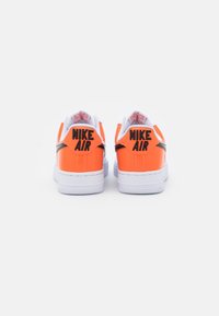 Nike Air-sneakers med en glänsande orange läderöverkappa, vit gummisula och svart logotyp på hälen, med en vadderad krage.