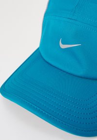 Jasnoniebieska czapka Nike z zakrzywionym daszkiem i małym białym logo swoosh Nike na przedniej części.