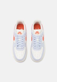 Die Nike Air Force 1 Sneaker verfügen über ein hellblaues Lederobermaterial mit weißen Akzenten, orangefarbenen Branding und einer perforierten Zehenbox für Atmungsaktivität.