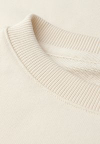 Crème-kleurige katoenen sweatshirt met een geribbelde ronde hals en een zachte textuur, voorzien van contrasterende stikseldetails.