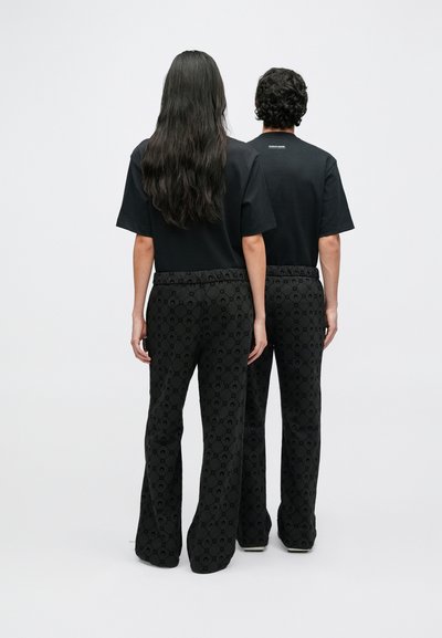 Czarne koszulki połączone z rozkloszowanymi czarnymi spodniami z delikatnym wzorem. Materiał jest gładki, o luźnym kroju i elastycznym pasie.
