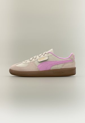 Lavprofil beige Puma sneaker med pink stribe, brun sål og grå snørebånd på neutral baggrund, set fra siden.