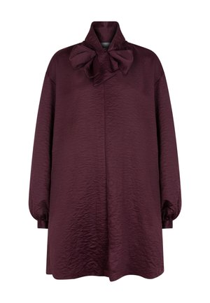 Blouse oversize bordeaux avec une finition texturée, dotée d'un col haut et d'un grand nœud au niveau du décolleté, manches longues bouffantes.