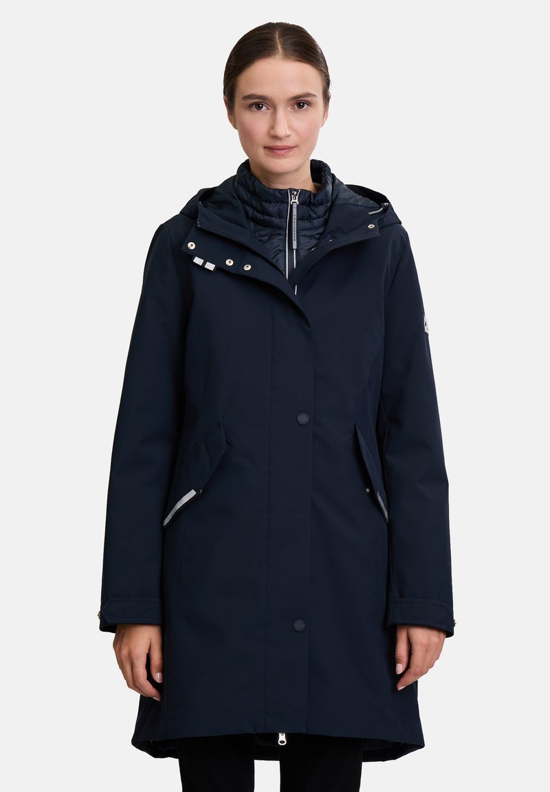 Navy waterproof coat with a zippered hood, button closure, side pockets, and quilted inner lining. Features reflective accents and a sleek design.