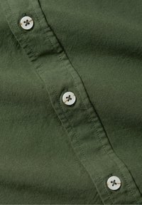 Olijfgroene overhemdd blouson met een gladde stofstructuur, witte knopen met vier gaten en een net gestikte patijng.