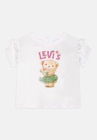 Camiseta de algodón blanco con mangas cortas acampanadas, que presenta un gráfico colorido de un oso de peluche con una falda hula y el texto "Levi's" en rosa.
