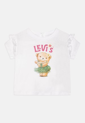 Camiseta de algodón blanco con mangas cortas acampanadas, que presenta un gráfico colorido de un oso de peluche con una falda hula y el texto "Levi's" en rosa.