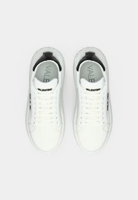 Baskets en cuir blanc avec un talon en cuir verni noir, des lacets plats et le logo "VALENTINO" sur les côtés et la languette.