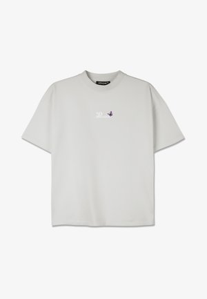 Svijetlosiva majica s okruglim izrezom, kratkim rukavima i malim ljubičastim dizajnom leptira u području lijeve strane prsnog koša. Mekana tekstura tkanine.