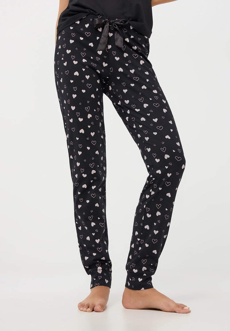 Pantaloni del pigiama neri con un motivo a cuori in diverse tonalità di rosa e bianco; presentano un elastico in vita con un laccio in satin nero.