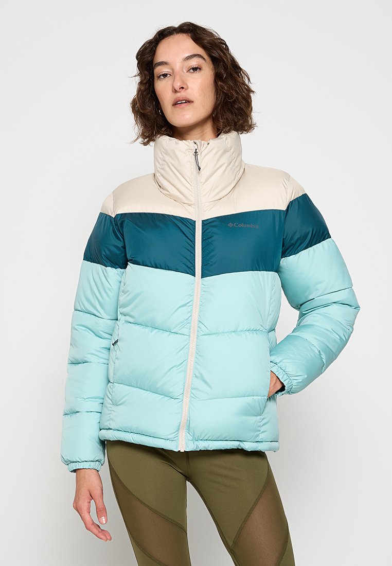 Chaqueta acolchada con un diseño en bloques de color en tonos azul petróleo, azul claro y crema. Cuello alto, cremallera completa y bolsillos laterales. Textura suave.