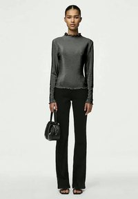 Μεταλλική μαύρη μπλούζα μακρυμάνικη με καπιτονέ λαιμόκοψη, συνδυασμένη με εφαρμοστά μαύρα παντελόνια καμπάνα και μια μικρή μαύρη τσάντα. Λεπτή υφή.