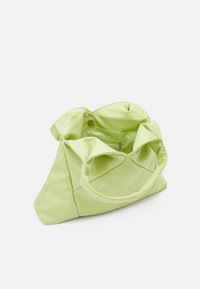 Světlazelená měkká kabelka s širokým držadlem, otevřený vršek ukazující vnitřní zipovou kapsu a zavírání na patentku na jednobarevném pozadí.