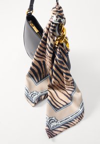 Μαύρη δερμάτινη τσάντα χειρός σε καμπυλωτό σχήμα, με χρυσή αλυσίδα και μια μοτίβο μεταξωτή φουλάρι σε μπεζ και καφέ λωρίδες τίγρης.