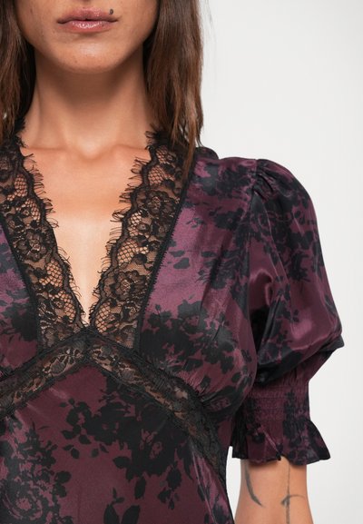Purple satin dress featuring a floral black lace design, deep V-neckline, short puff sleeves, and lace trim details.