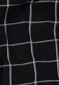 Svart tyg med ett rutmönster i vita linjer, med en slät textur och matt yta.