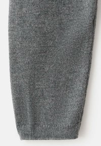 Manșon de pulover gri tricotat, cu textură netedă și manșetă striată. Materialul pare moale, cu un model uniform, ușor pătate.