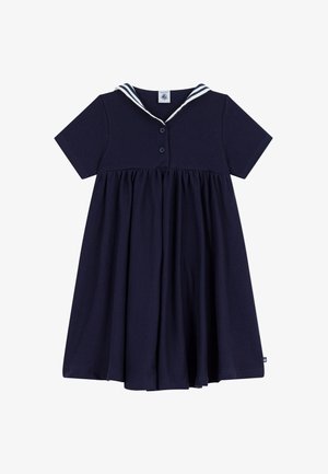 Marineblå kjole med korte ermer, sjømannskrage med hvite striper, tre knapper på overdelen og et rynket skjørt.