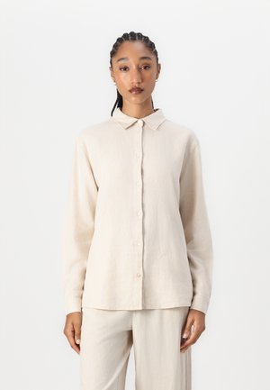 Beige long-sleeve shirt with a button-up front, collar, and relaxed fit. Made of textured fabric, paired with matching light beige pants.