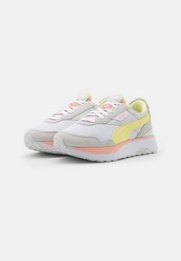 Baskets Puma avec tige en mesh blanc et en daim gris, ornées de touches jaune et rose. Bout arrondi et semelle rembourrée pour un confort optimal. Fermeture à lacets.