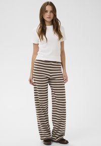 Biela košeľa s krátkym rukávom z bavlneného zmesi spárovaná so širokými hnedo-bielymi pruhovanými nohavicami. Hladká textúra; uvoľnený strih; ležérny dizajn.