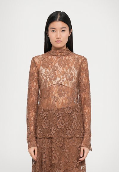 Brune kantblouse met lange mouwen, hoge hals en bloemenpatroon. Zachte textuur en doorschijnende delen creëren een gelaagd uiterlijk.