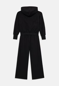 Mono negro con capucha, mangas largas, cinturilla elástica y diseño de pierna ancha. Fabricado con una tela suave y texturizada.