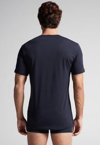 Námorně modré tričko s krátkým rukávem z měkké, hladké látky; má jednoduchý kulatý výstřih a bezšvový design zad.