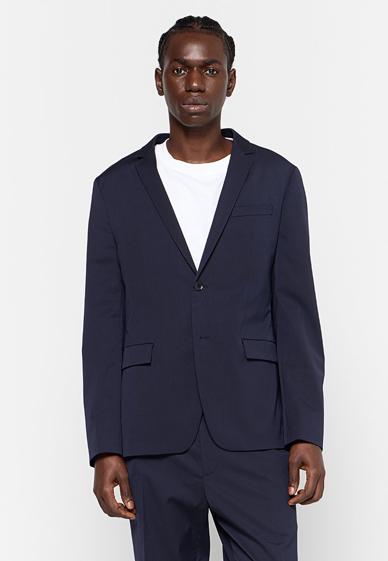 Blazer bleu marine avec une fermeture à un seul bouton, des revers crantés, une poche poitrine et deux poches à rabat à l'avant ; texture de tissu lisse.