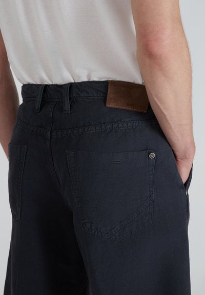 Pantalones cortos azul marino con un corte relajado, hechos de algodón texturizado. Presenta un parche de cuero marrón con la marca y dos bolsillos traseros.