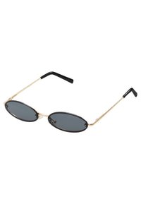 Gafas de sol ovaladas negras con lentes oscuros, delgadas montura de metal dorado y puntas de acetato negro. Diseño elegante con estética minimalista.