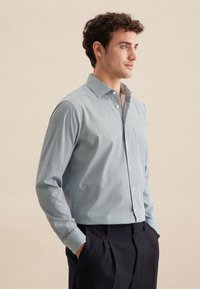 Camicia a quadri blu chiaro e bianca, con maniche lunghe, colletto a punta e vestibilità slim. Tessuto liscio con una lieve lucentezza.