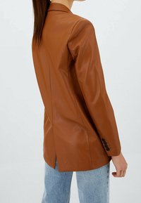 Ruskea nahkableiseri, jossa on istuva malli, notched-lapeli ja yksittäinen halkio. Hihoissa mustat napit ja sileä pinta.